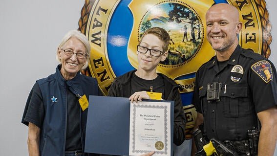 Wish Kid Johnny receiving his certificate with Linda Pauling and police officer
