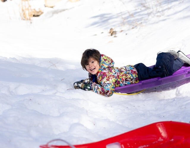 Wish kid Nash sledding in the snow