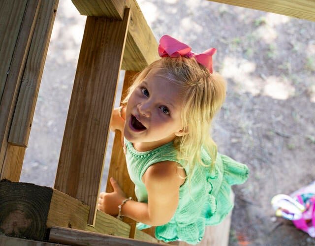 Wish kid Macie climbing a ladder to her new treehouse