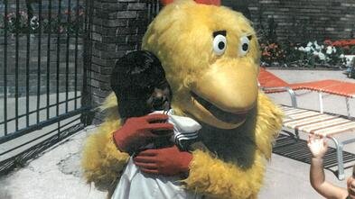 Girl hugging chicken mascot 