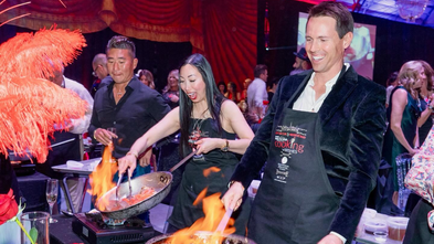 People wearing aprons and cooking at event.