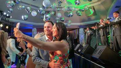 Man and woman taking a selfie with the live band on stage at WMP.