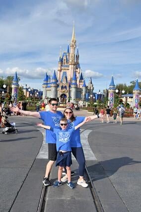Noah and his family pose in front of the castle at Disney World